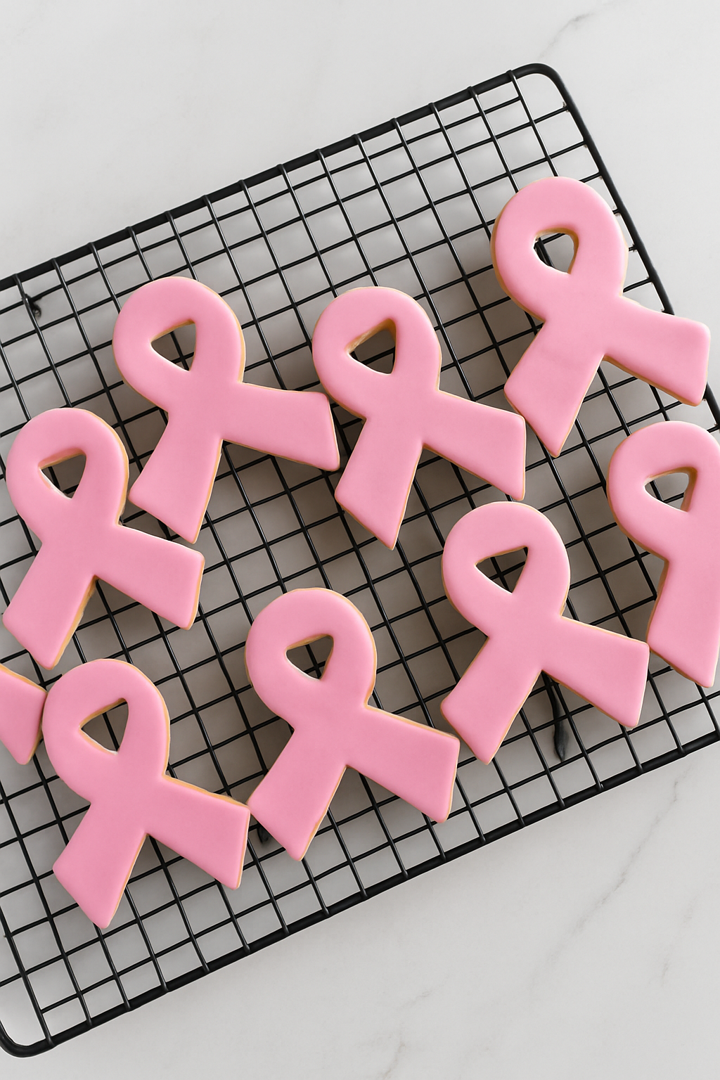 Biscuits artisanaux en forme de ruban rose décorés en pâte à sucre, symbole de la lutte contre le cancer du sein – gourmandise solidaire Octobre Rose