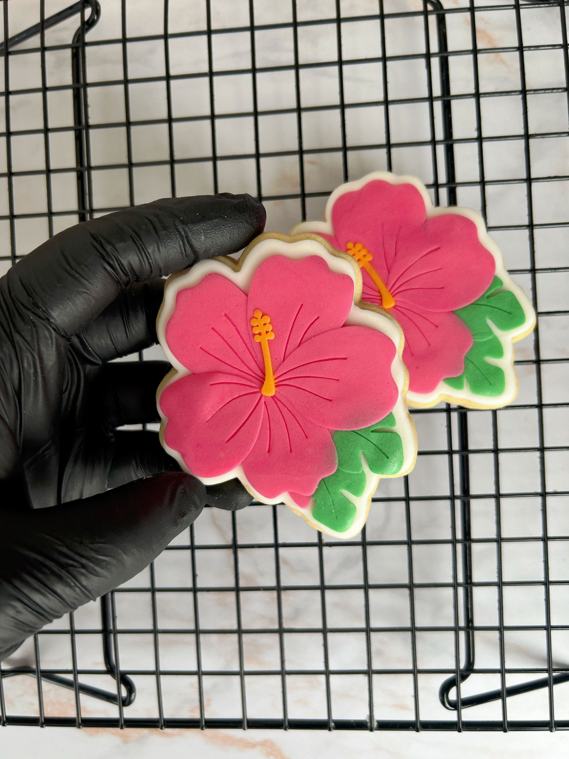 Biscuit décoré Hibiscus posé sur grille de refroidissement, création Les Folies Gourmandes de Judy.