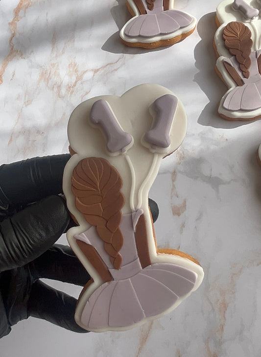Biscuit décoré en pâte à sucre représentant une petite princesse avec robe violette, tresse brune et ballons d’anniversaire, création artisanale personnalisée.